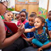 Children sitting on the ground while seeing a book