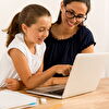Mother and daughter laughing and watching laptop