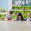 Children Lying on the Ground in Front of Green Shelves