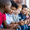 Teenagers Sitting in Line With Smartphones